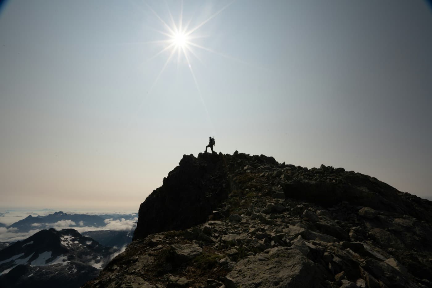 Bergsteiger auf einem Gipfel im Gegenlicht